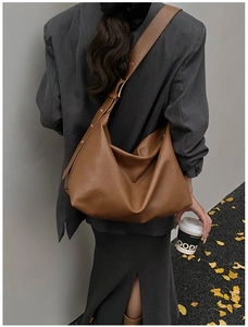 Brown soft leather hobo bag with wide shoulder strap styled in autumn street scene