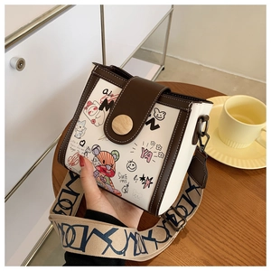 Detail of cartoon graffiti crossbody bag with brown leather trim and wide jacquard strap