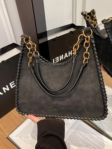 Retro black suede shoulder bag with braided edges and gold chain strap in fashion setting