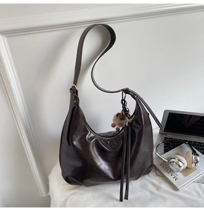 Detail der dunkelbraunen Hobo-Tasche mit Quasten-Reißverschluss und Plüsch-Anhänger