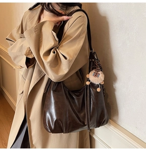 Detail einer dunkelbraunen Vintage Hobo-Tasche mit süßem Plüsch-Schaf-Anhänger am Riemen