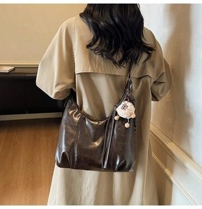 Detail der Vintage-Tote-Bag aus braunem Leder mit weißem Plüsch-Lamm-Anhänger