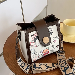 Chic graffiti bucket bag with bear patterns, brown trim and wide geometric strap