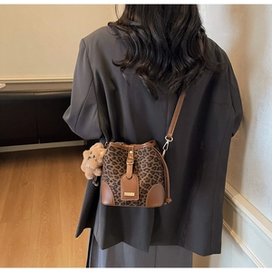 Rear view of a model wearing the leopard print bucket bag with a cute bear plush pendant
