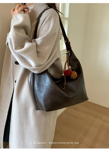Detail of dark brown retro tote bag with textured leather and decorative pom-pom charms