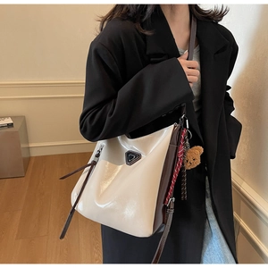 Detail of cream patent leather tote with brown trim and cute bear charm accessory