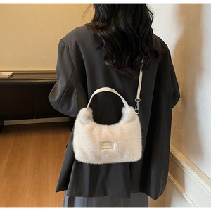 Détail du sac en peluche blanche avec poignées en cuir et crochets métalliques amovibles