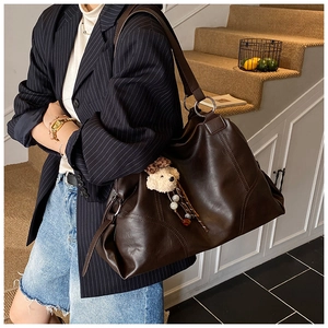 Grand sac fourre-tout marron foncé avec pendentif ours porté avec un costume à rayures