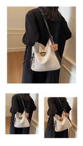 Detail of white glossy hobo bag featuring a plush bear pendant and triangular metal logo
