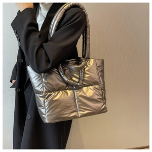 Zijaanzicht van metallic zilveren gewatteerde puffer tote tas met brede schouderband