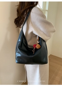 Detail of black retro tote bag with smooth faux leather texture and fluffy charm