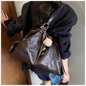 Détail du sac cabas marron foncé avec coutures patchwork et pendentif en peluche
