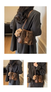 Detail of leopard print bucket bag featuring brown leather trim and cute plush bear charm