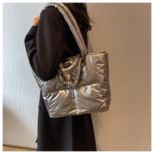 Detail van zilveren gewatteerde puffer tote bag met glanzende afwerking en vulling