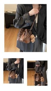 Detail of leopard print bucket bag featuring brown leather straps and a plush bear charm