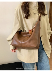 Detail of vintage brown leather tote bag with decorative tassel charms on the side