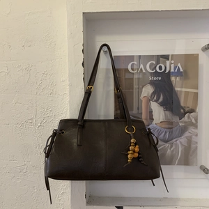 Detail of dark brown faux leather bag with side drawstrings and ethnic beaded charm