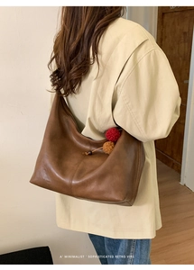 Detailed view of large brown retro tote bag with dual-color plush charm and stitching