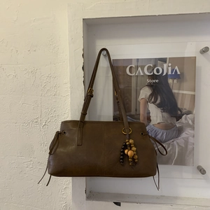 Detail of vintage brown shoulder bag with stitching and ethnic style wooden bead charm