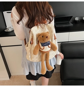 Detail of cream backpack with bear pattern and 3D plush bear charm for daily use