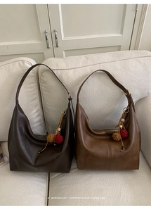 Detail view of two vintage leather tote bags in dark and light brown with colorful charms