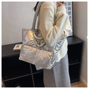 Detail van de zilveren gewatteerde dons-tote tas met metallic textuur en schouderband