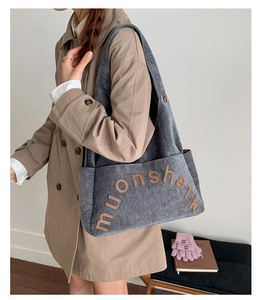 Détail du sac cabas gris avec lettres muonshark marron porté par un mannequin en trench