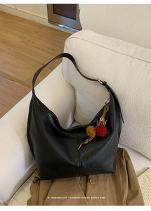 Detail of minimalist black leather hobo bag with vintage tassel and gold metal buckle