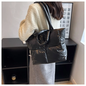 Detail van een grote zwarte gewatteerde shopper met gevoerde handvatten op een model