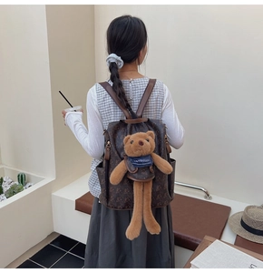 Detail view of brown monogram backpack with vintage bear pattern and plush bear charm