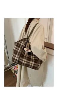 Detail of checkered canvas tote bag with brown leather straps and plush rabbit charm