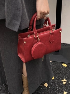 Fashionable dark red matte PU leather handbag with a round purse charm on gravel background