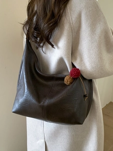 Vintage brown leather tote bag with plush charm shown on model in a minimalist setting