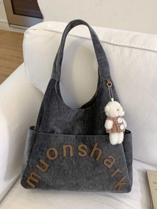 Grand sac cabas en velours côtelé gris foncé avec breloque ours et écusson sur sofa