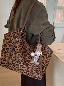 Large leopard print tote bag with brown straps and funny rabbit plush charm shown on shoulder