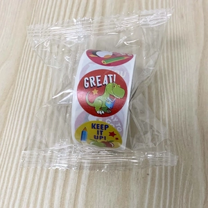 Roll of cartoon reward stickers in transparent packaging on a wooden background