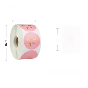 Macro detail of a 1-inch pink gold foil thank you sticker roll with dimension markings