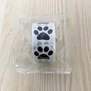 Detail view of round black paw print stickers roll on light wooden background
