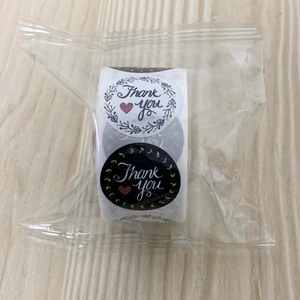 Detail of round Thank You labels roll with floral wreath in transparent packaging