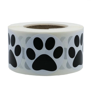 Roll of white circular stickers featuring black paw print designs with paper core