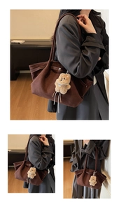 Détail d'un sac cabas en daim marron avec un joli pendentif ours en peluche doux