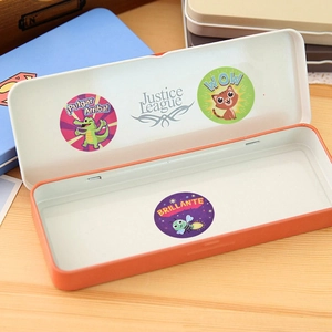 Orange rectangular metal stationery box featuring colorful cartoon reward stickers on a desk