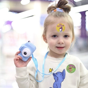 Sky blue kids digital camera with white lens ring held by a girl with reward stickers