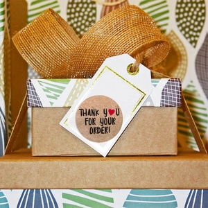 Round kraft paper thank you stickers with red hearts on a gift box package