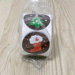 Detail view of round Christmas stickers roll featuring festive holiday patterns in plastic bag