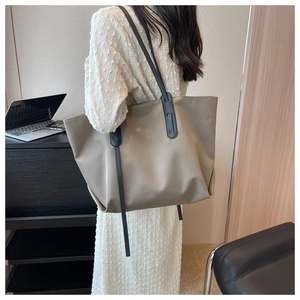 Détail d'un grand sac cabas kaki porté par un mannequin pour un look de bureau élégant