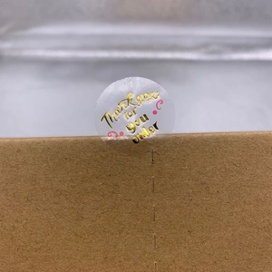 Transparent round thank you sticker with gold foil lettering on brown craft box