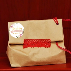 Brown kraft paper gift bag with red lace decoration and Thank You flower sticker