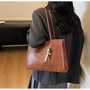 Side view of a large brown vintage tote bag with beaded charm for daily commuting