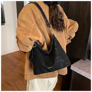 Detail view of large black tote bag featuring contrast white stitching and gold buckles